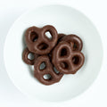 Bite-size pretzels fully dipped in smooth dark chocolate, plated on white.
