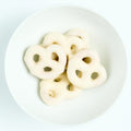 Bite-size pretzels fully dipped in smooth white chocolate, plated on white.
