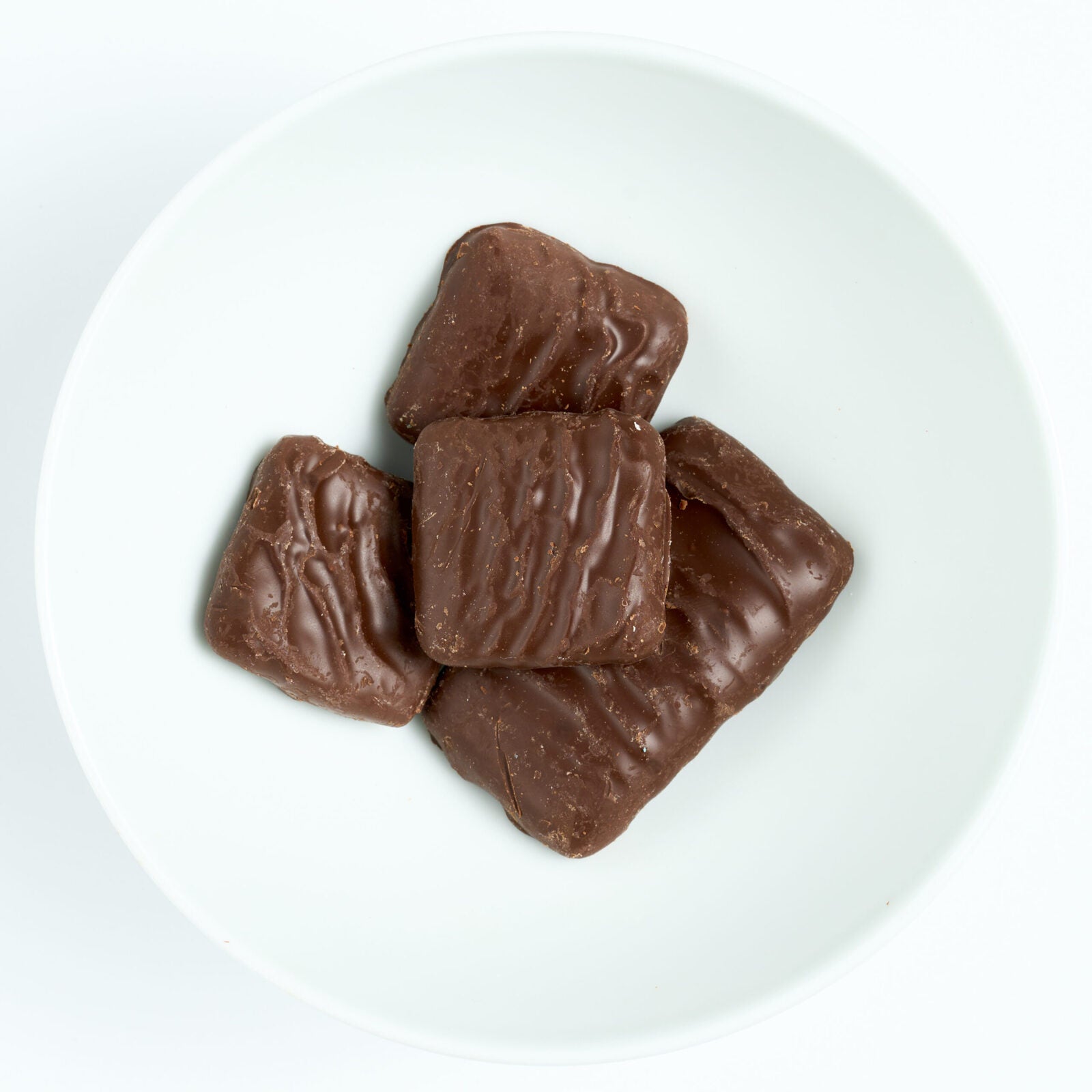 Bite-size graham cracker squares fully coated in dark chocolate, plated on white.