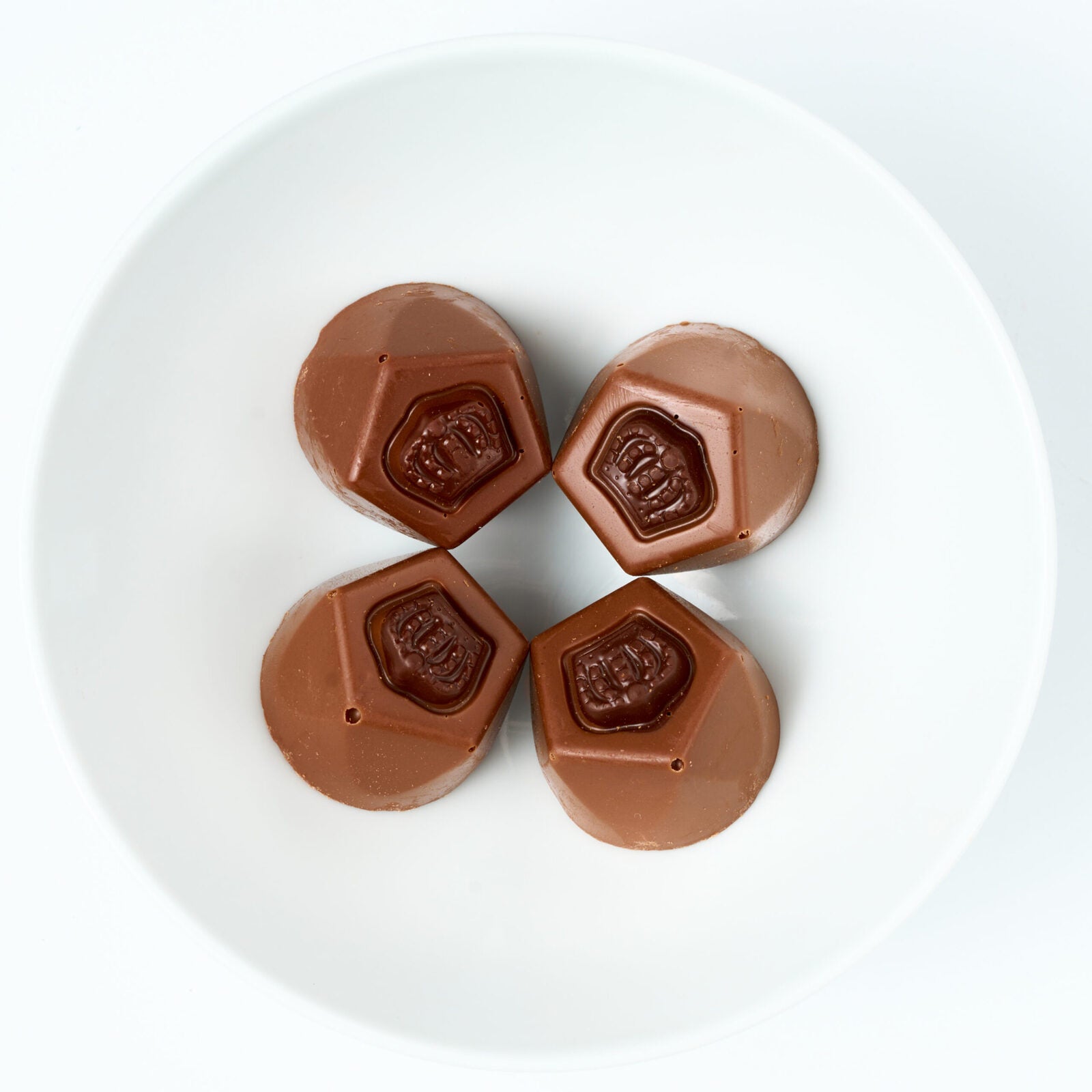 Sugar-free milk chocolate espresso truffles with embossed tops on a white plate.